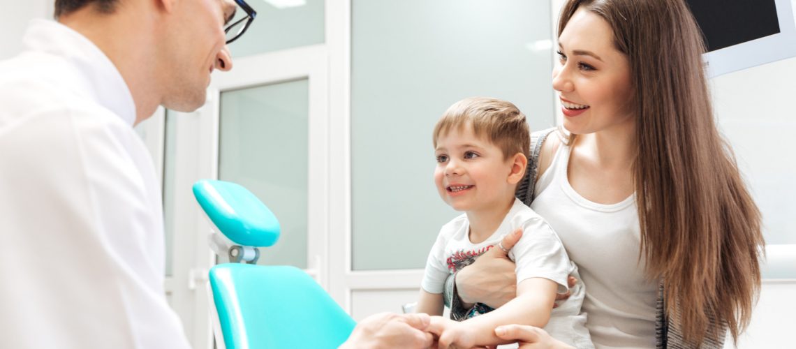 Smiling mother and her little son visiting dentist